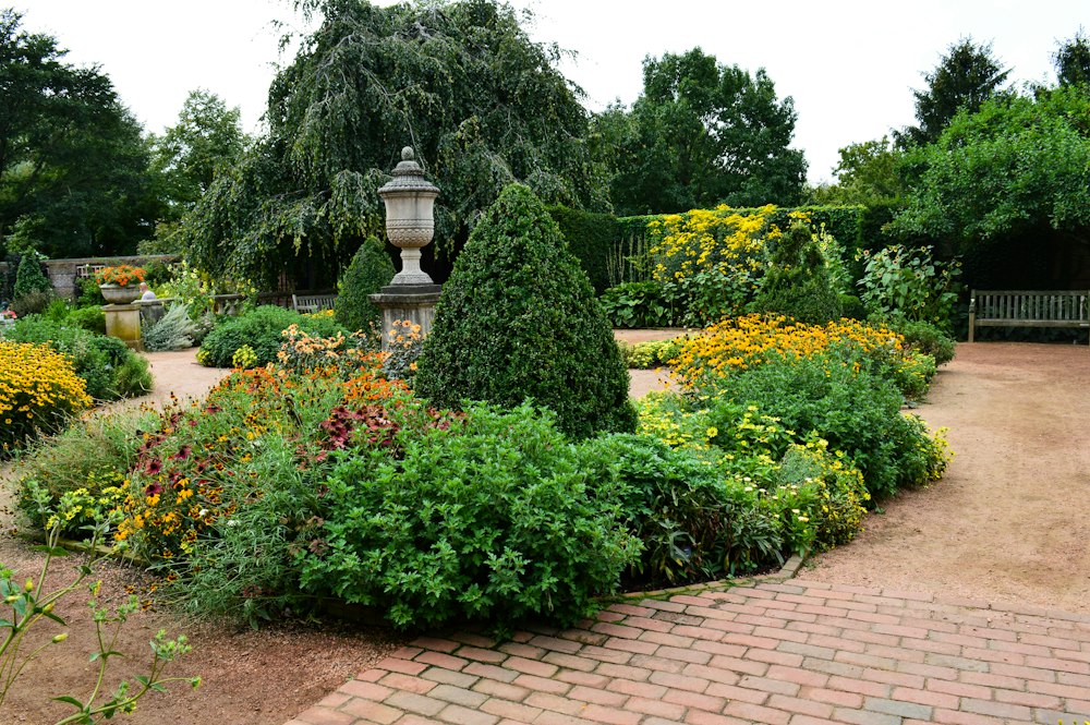 A formal garden with planted beds and a brick path
